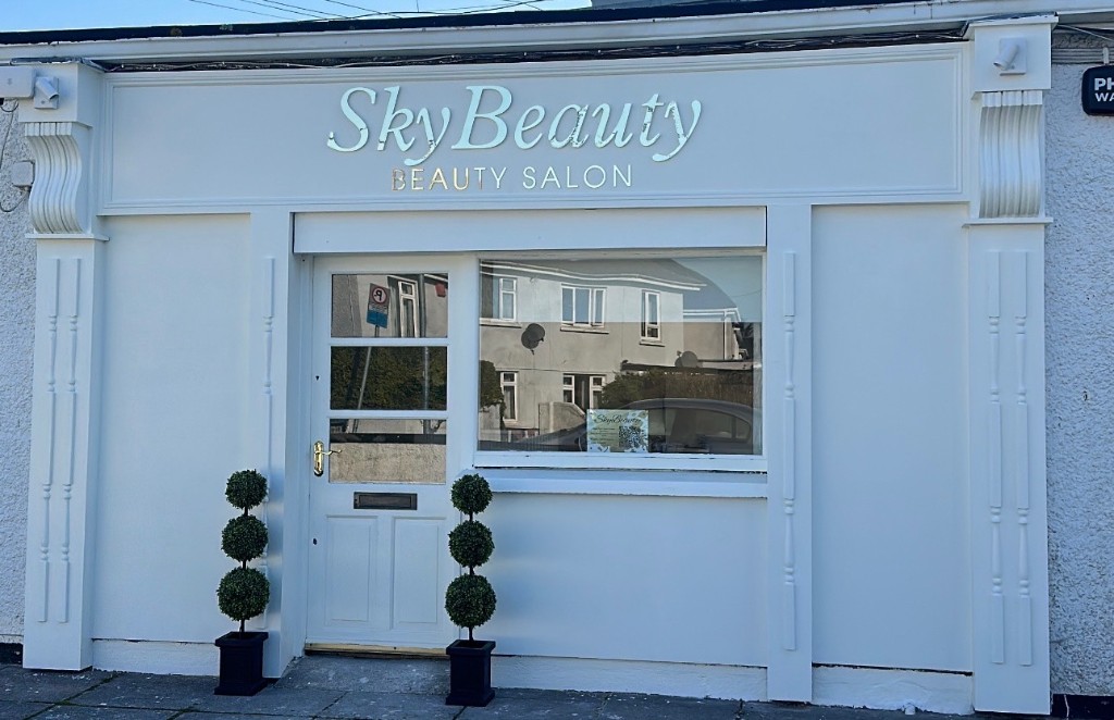 Sky Beauty salon storefront exterior with white facade, gold signage, and topiary planters