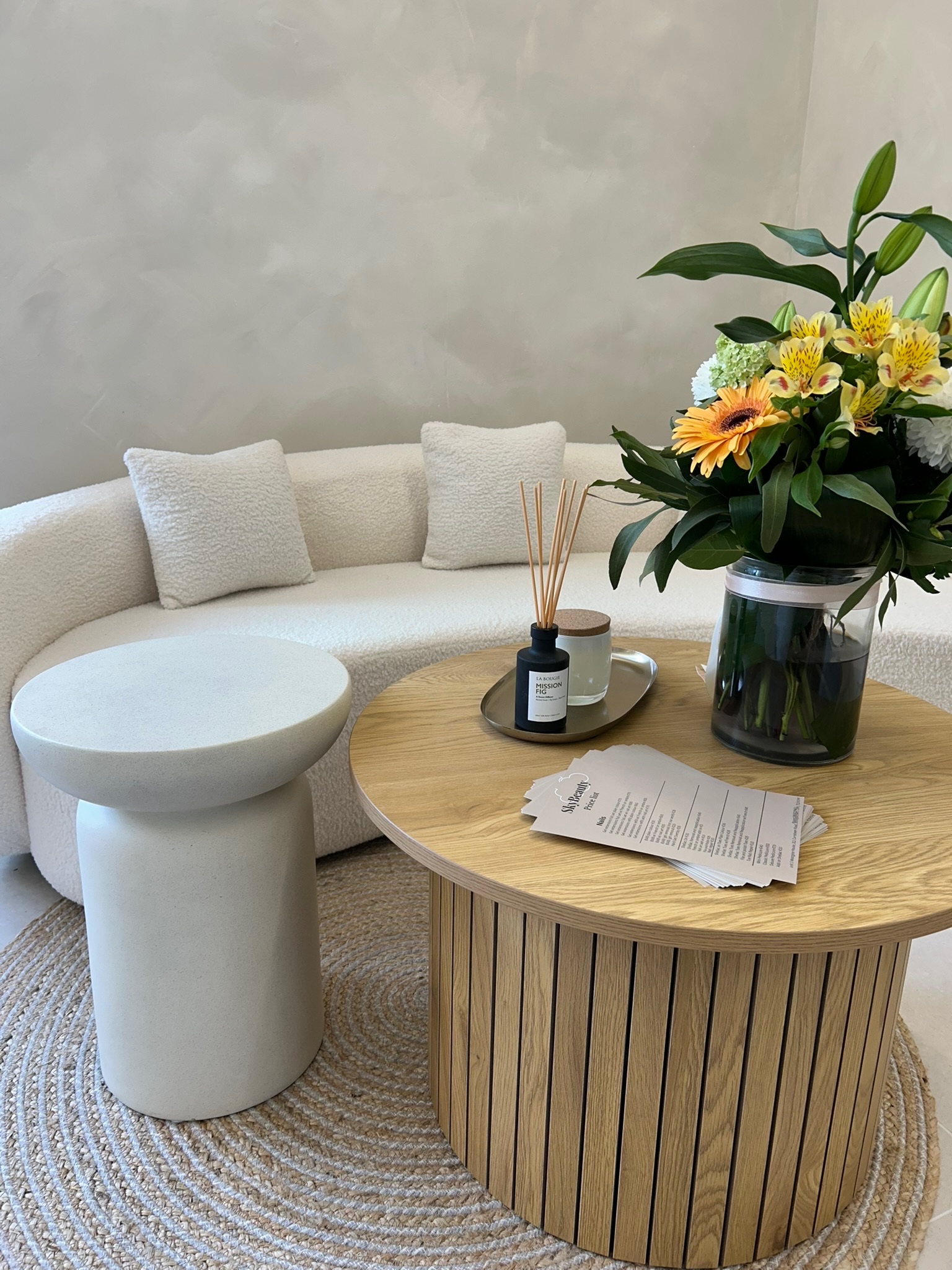 Sky Beauty waiting area with curved white sofa, floral arrangement, and modern decor