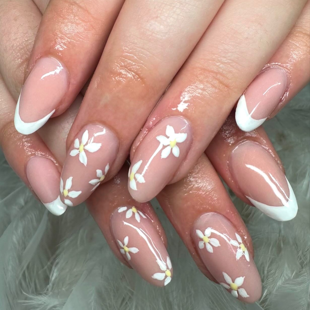 Soft pink almond nails with white French tips and daisy nail art