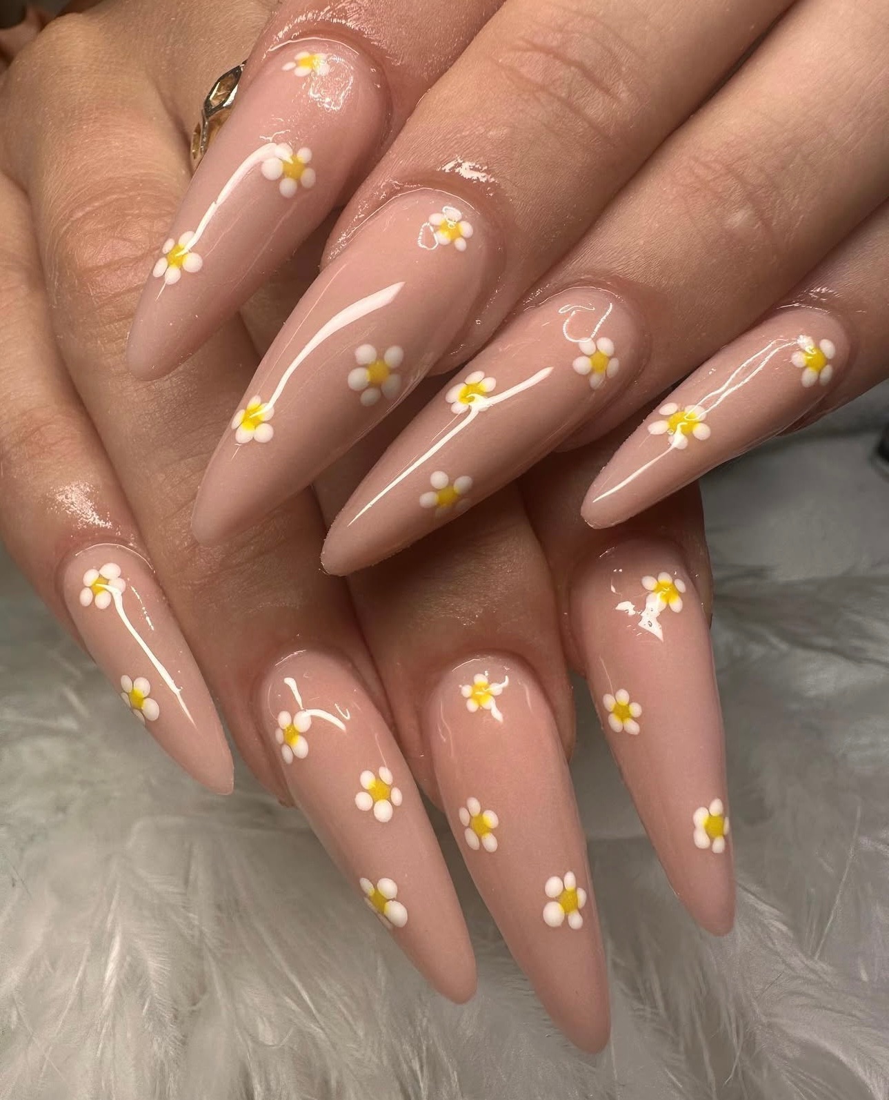 Hands with long almond-shaped BIAB nails featuring white daisy nail art