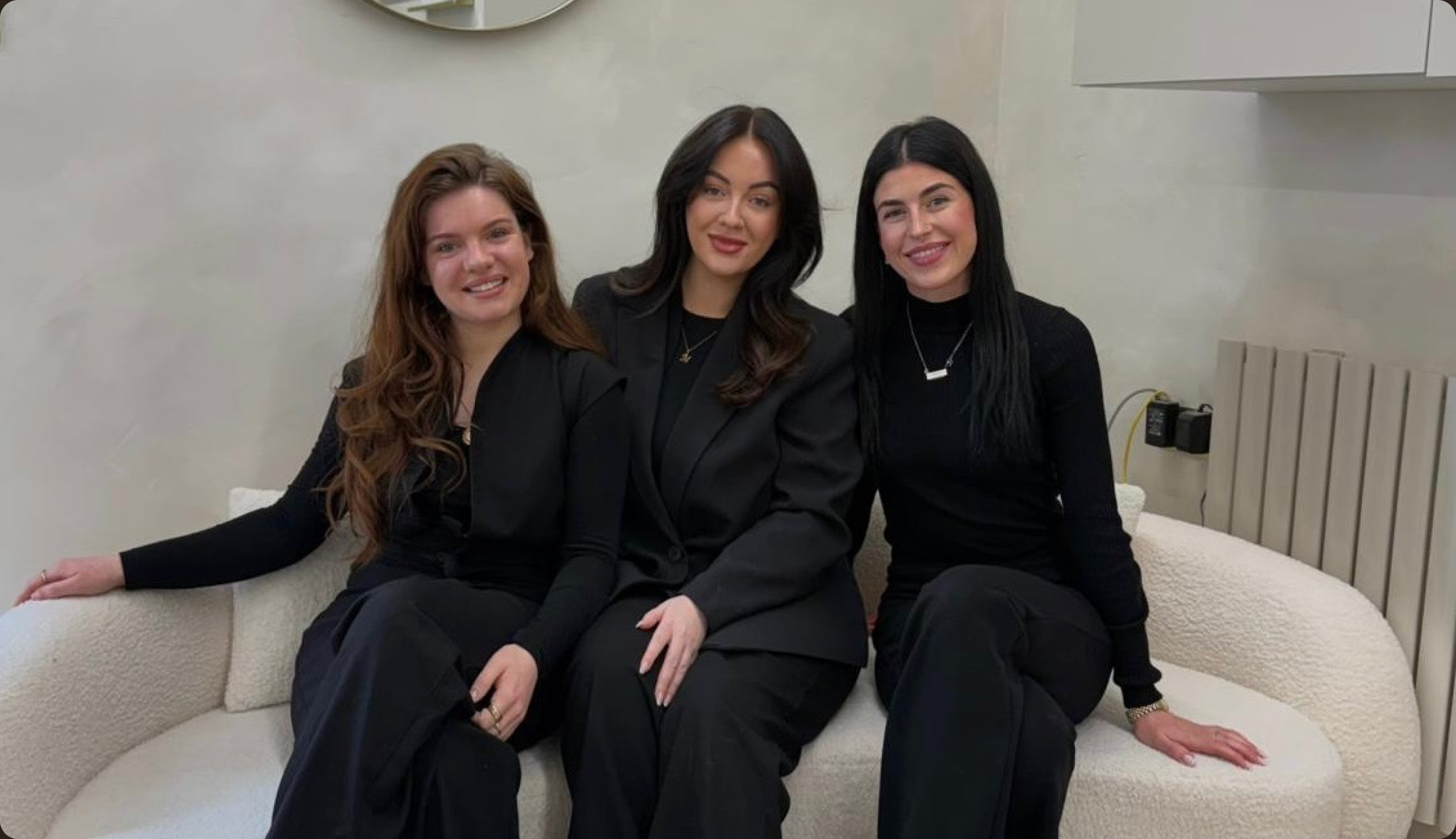 Three SkyBeauty & Laser therapists seated together on a white sofa